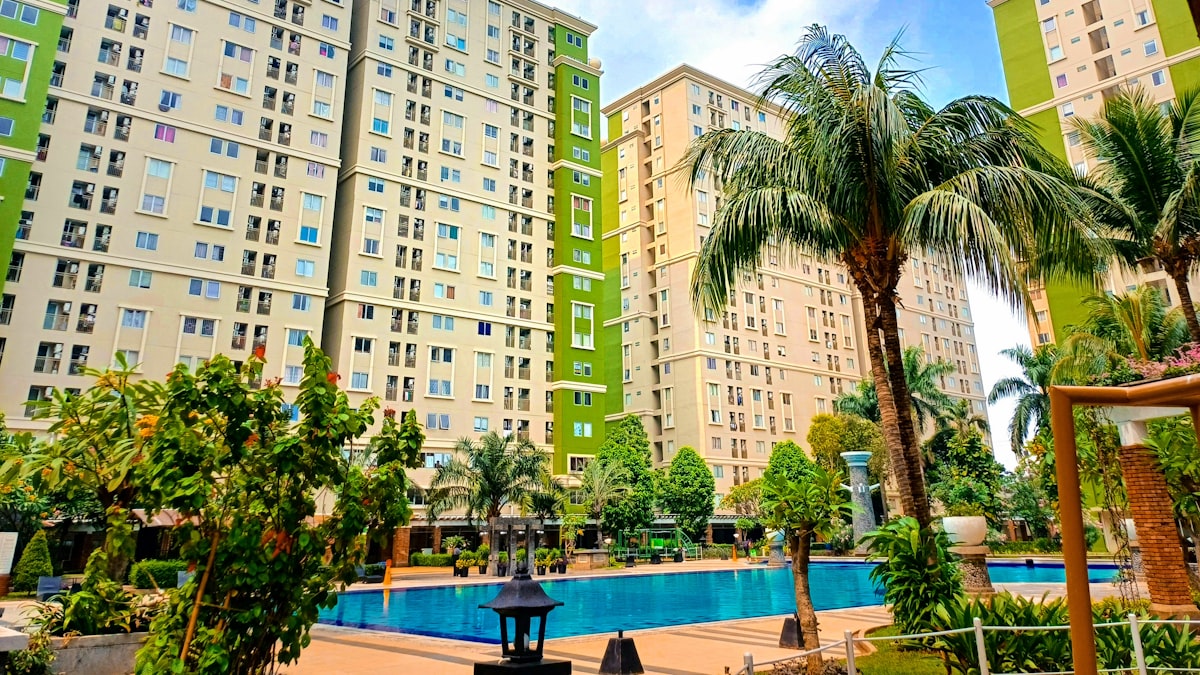 Piscina de condomínio cercada por prédios e área verde